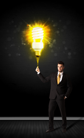 Businessman hold a shining eco-friendly idea bulb on a black backgroundの写真素材