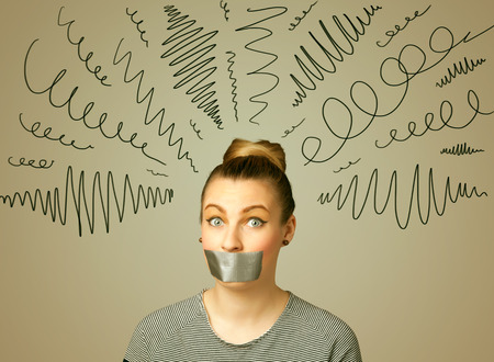 Young woman with taped mouth and curly lines around her headの写真素材