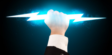 Business man holding glowing lightning bolt in his hands conceptの写真素材