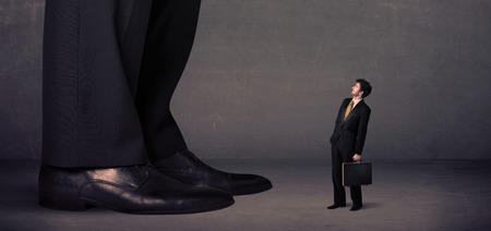 Huge legs with small businessman standing in front concept on backgroundの写真素材
