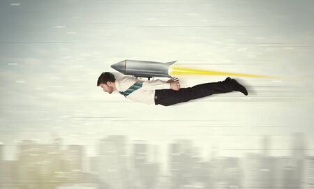 Superhero business man flying with jet pack rocket above the city conceptの写真素材