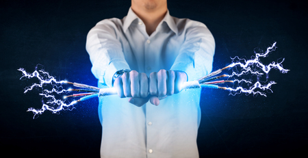 Business person holding electrical powered wires concept on backgroundの写真素材