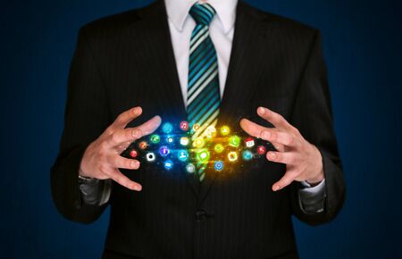 Businessman holding a shining app icon cloud in front of his bodyの写真素材