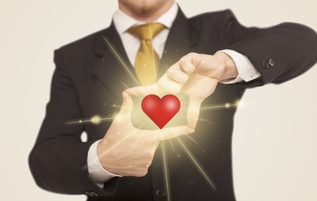 Hands creating a form with shining red heart in the centerの写真素材