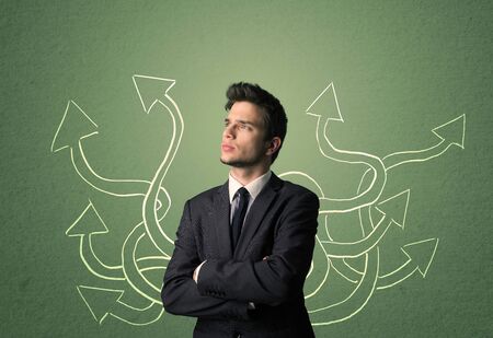 Young Businessman with thoughtful expression with tangled arrows coming out of his backの写真素材