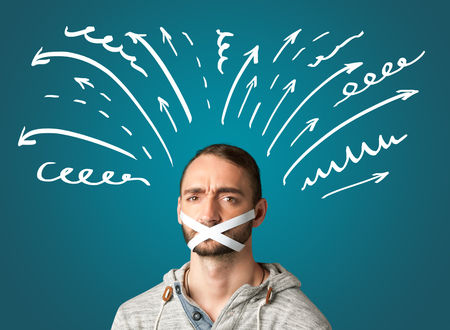 Young man with taped mouth and white drawn lines and arrows around his headの写真素材