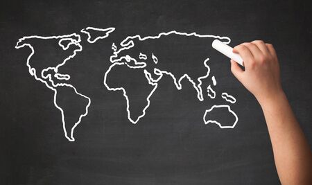 A teacher drawing the map of the world on a blackboard with a chalk