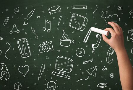 A person drawing media and communication icons on school blackboard with chalkの写真素材