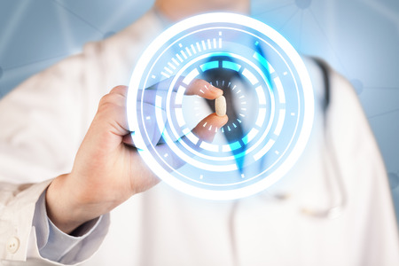 A male  doctor in white coat showing a glowing pill in blue, white circlesの写真素材