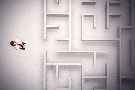 Confused businessman standing at a maze wall with grungy backgroundの写真素材