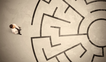 Lost business man looking for a way in circular labyrinth conceptの写真素材