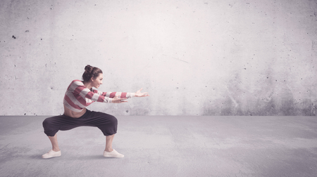 A beautiful young hip hop dancer dancing contemporary urban street dance in empty clear grey wall background concept.の写真素材