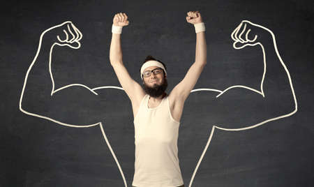A young male with beard and glasses posing in front of grey background, thinking about lifting weight with big muscles, illustrated by white drawing concept.の写真素材