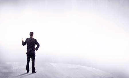 Young sales businessman in elegant suit standing with his back in empty white space background...