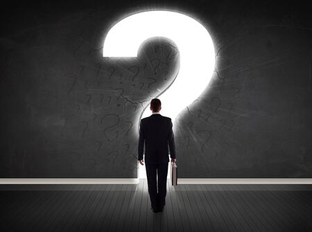 Business man looking at wall with a bright question mark conceptの写真素材