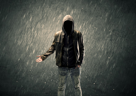 A dangerous unrecognizable faceless criminal standing in front of grainy urban wall conceptの写真素材