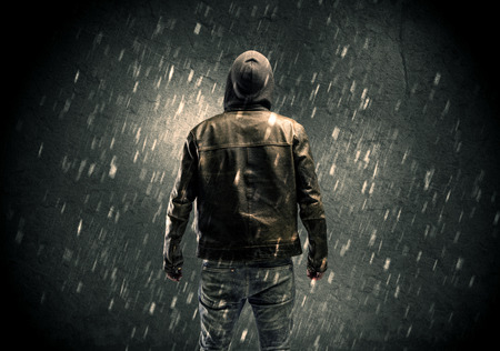 A faceless misterious man in hoodie and leather jacket standing in the dark with a visible silhouette conceptの写真素材