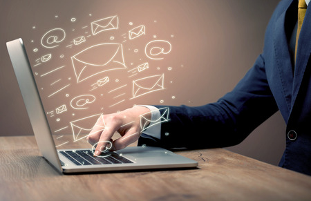 An office worker sending emails and communication with clients with the help of a portable laptop on desk conceptの写真素材