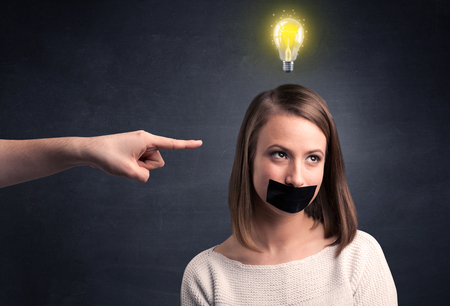 Caucasian hand pointing at female employee with a lightbulb above her headの写真素材