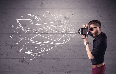 A hipster guy opening his point of view through looking a vintage camera concept with illustratied drawn arrows on urban wallの写真素材