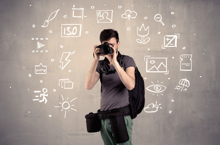 An amateur hobby photographer learning to use a professional digital camera with camera settings icons on the background wall conceptの写真素材