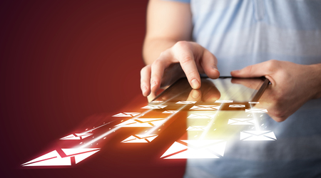 Hand holding tablet and sending email icons concept on backgroundの写真素材