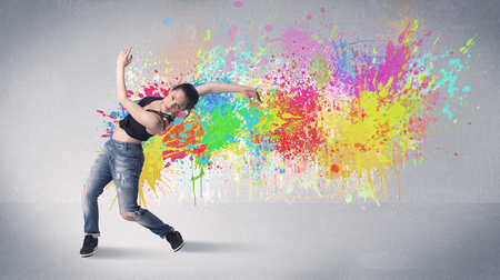 A funky contemporary hip hop dancer dancing in front of grey background with colorful bright paint splatter conceptの写真素材