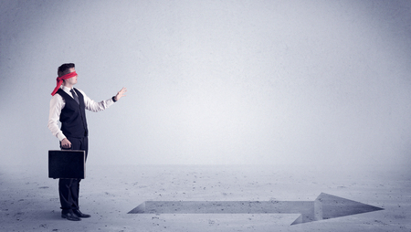 A confused blind salesman standing in front of a drawn arrow on the floor pointing in the right direction concept.の写真素材