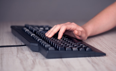 Close up of hand pressing keyboard buttons on desk