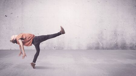 A beautiful young hip hop dancer dancing contemporary urban street dance in empty clear grey wall...