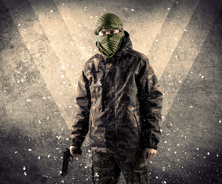 Portrait of a dangerous masked armed soldier with grungy light background