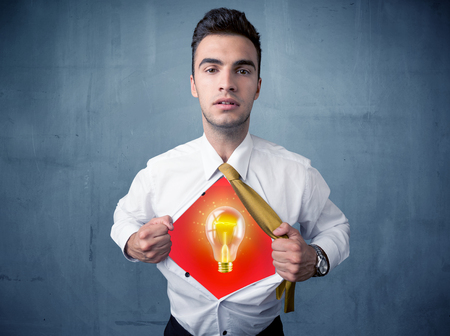 Businessman ripping off shirt and idea light bulb appears on his chest concept on backroundの写真素材