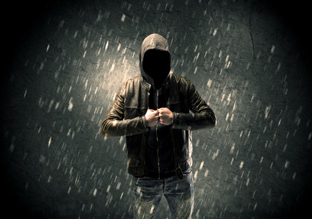 A faceless misterious man in hoodie and leather jacket standing in the dark with a visible silhouette conceptの写真素材