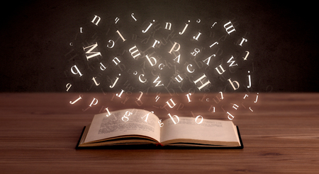 Glowing white alphabet letters coming out of an open bookの写真素材