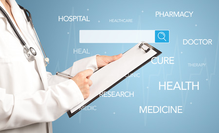 Female doctor holding notepad with blue background and search bar with hovering medical wordsの写真素材