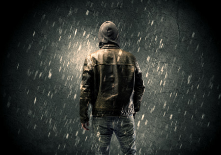 A faceless misterious man in hoodie and leather jacket standing in the dark with a visible silhouette conceptの写真素材