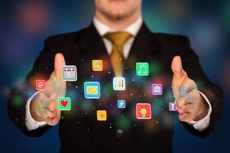 Elegant businessman holding colorful mixed media iconsの写真素材