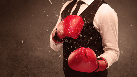 A strong sales person breaking something into pieces with red boxing gloves concept illustrated with glowing residue flying in the air.の写真素材