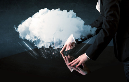 Male hands touching interactive table with a white cloud on itの写真素材