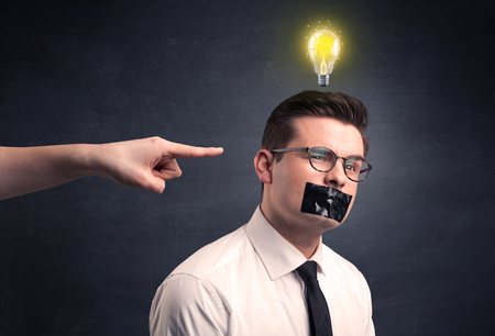 Caucasian hand pointing at businessman with a lightbulb above his headの写真素材