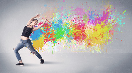 A funky contemporary hip hop dancer dancing in front of grey background with colorful bright paint splatter conceptの写真素材