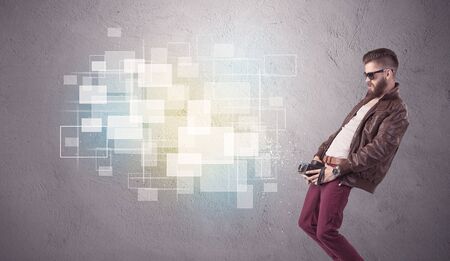 A funny stylish hipster guy capturing bright moments and glowing square pictures with a vintage photo camera illustration conceptの写真素材