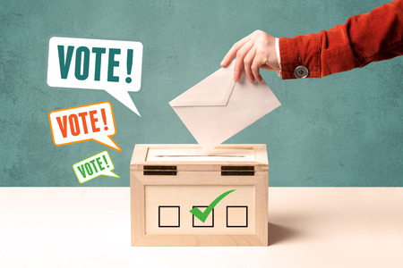 A hand placing a voting slip into a ballot boxの写真素材