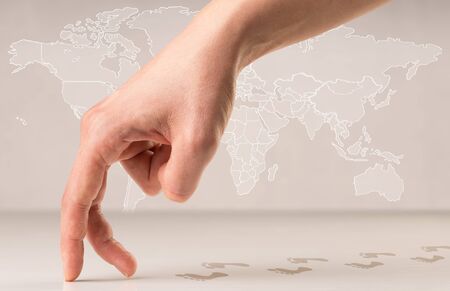 Female fingers walking with footsteps behind them and a world map in the backgroundの写真素材