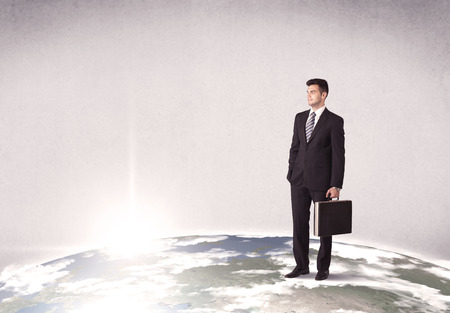 A young elegant office worker standing on top of a drawn world globe while celebrating his successful career concept.の写真素材