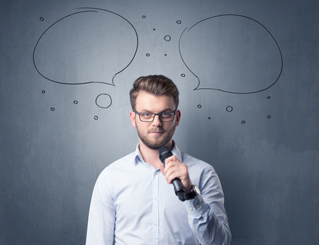 Businessman speaking into microphone with speech bubbles over his headの写真素材