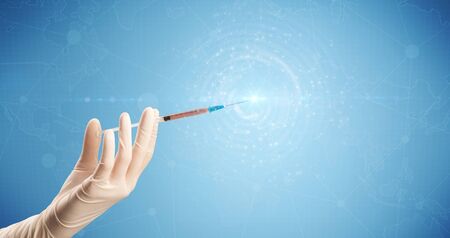 Female doctor hand holding syringe with blue background and shineの写真素材