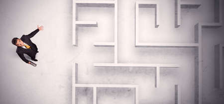 Confused businessman standing at a maze wall with grungy backgroundの写真素材