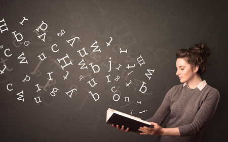 Casual young woman holding book with white alphabet flying out of itの写真素材