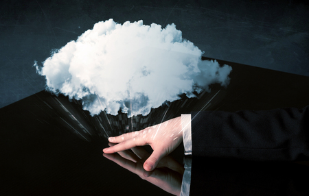 Male hands touching interactive table with a white cloud on itの写真素材